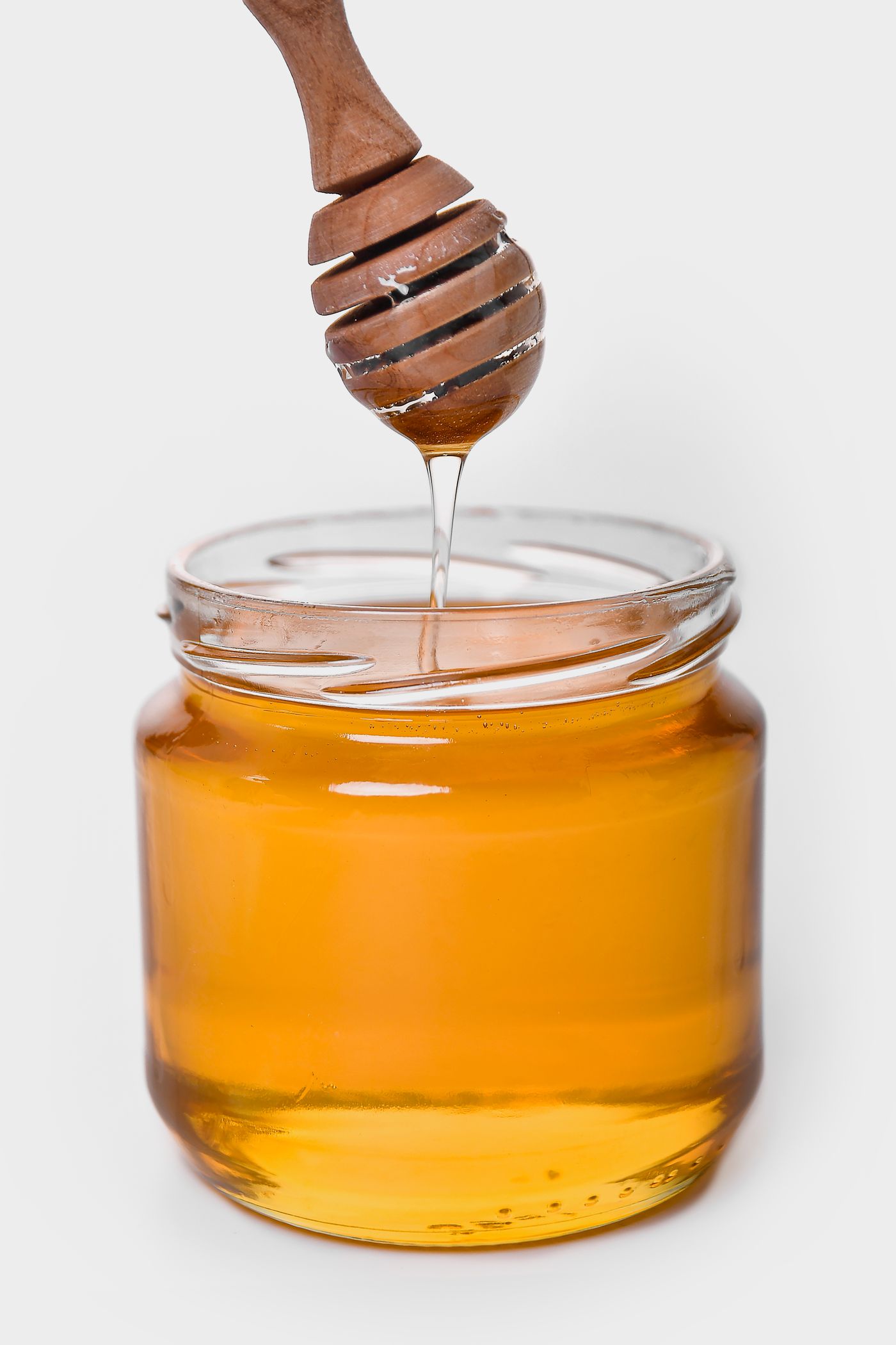 Raw honey being poured into a glass jar